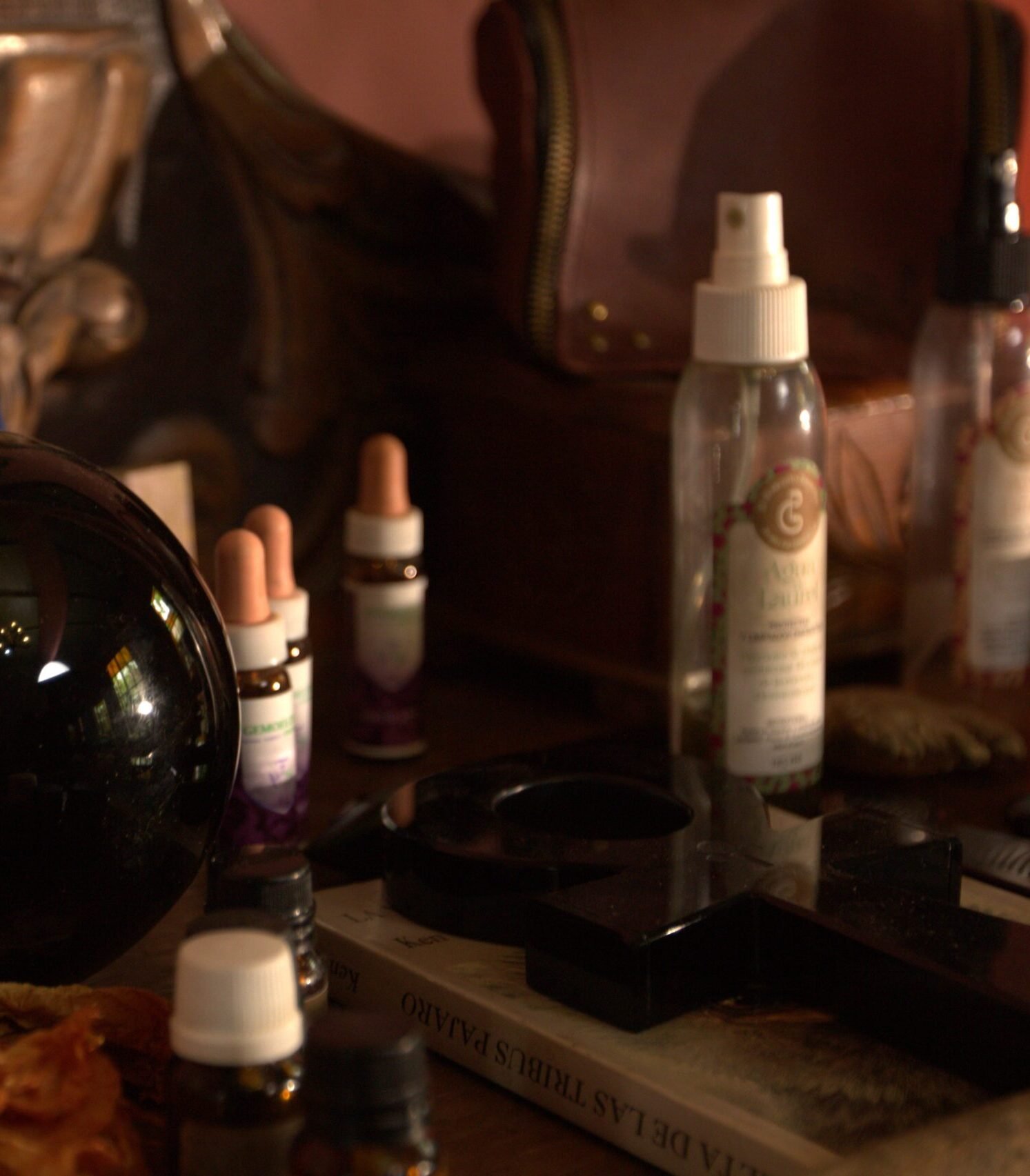 Mesa con frascos de esencias florales, spray energético, esfera negra, símbolo ankh y elementos de limpieza vibracional.