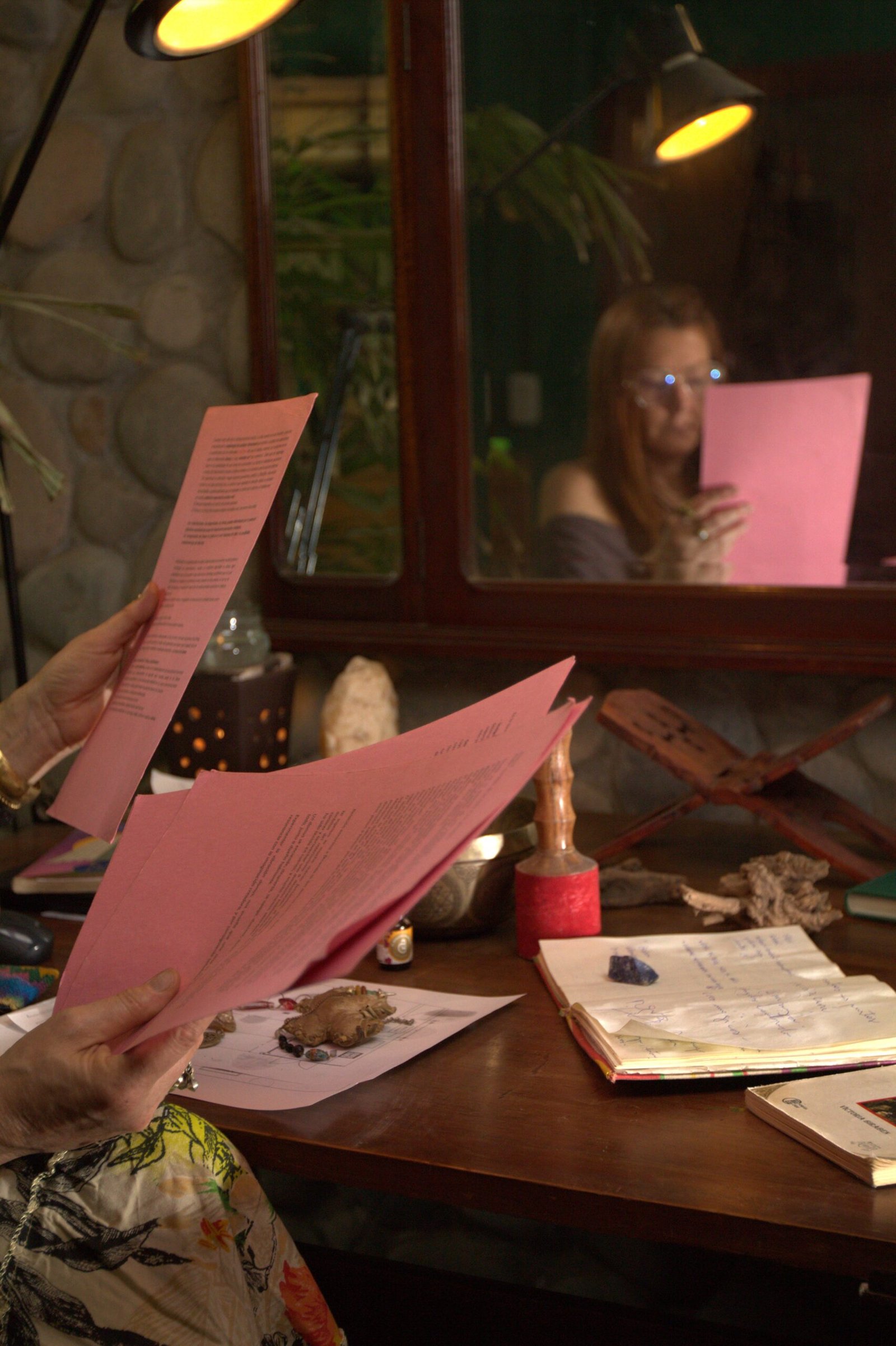 Mujer leyendo documentos en un espacio ritual con objetos energéticos y herramientas de armonización del hogar.